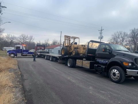 construction equipment towing on flatbed trailer pulled by heavy duty tow truck